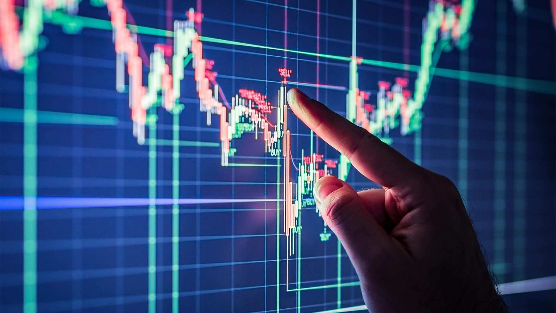 Closeup of a hand on a stock graph where the line is spiking, indicating this is when to sell