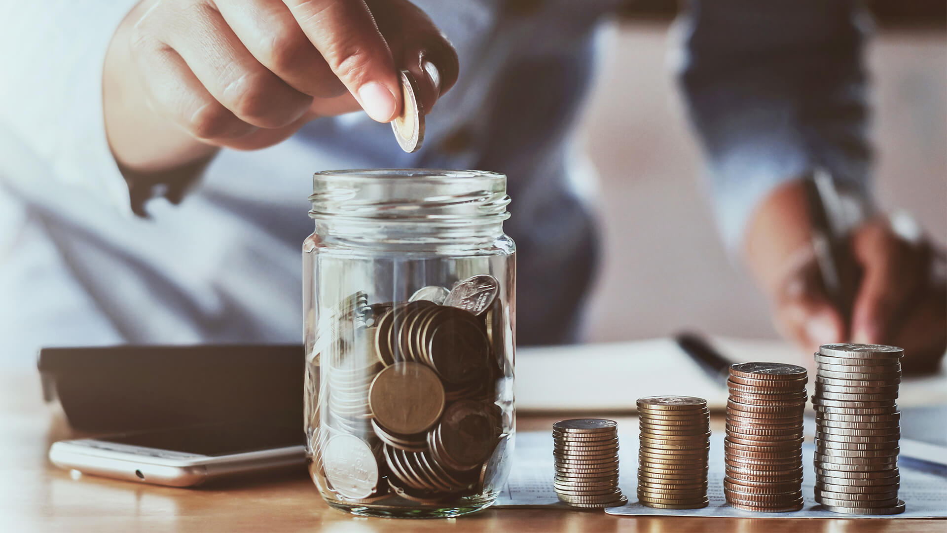 Accountant counting coins and adding them to a jar