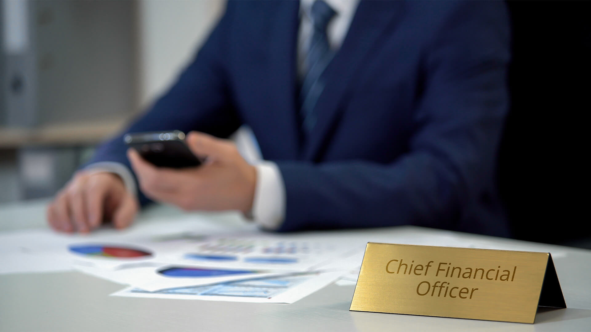 Business man sitting at a desk with a sign saying "Cheif Financial Officer"