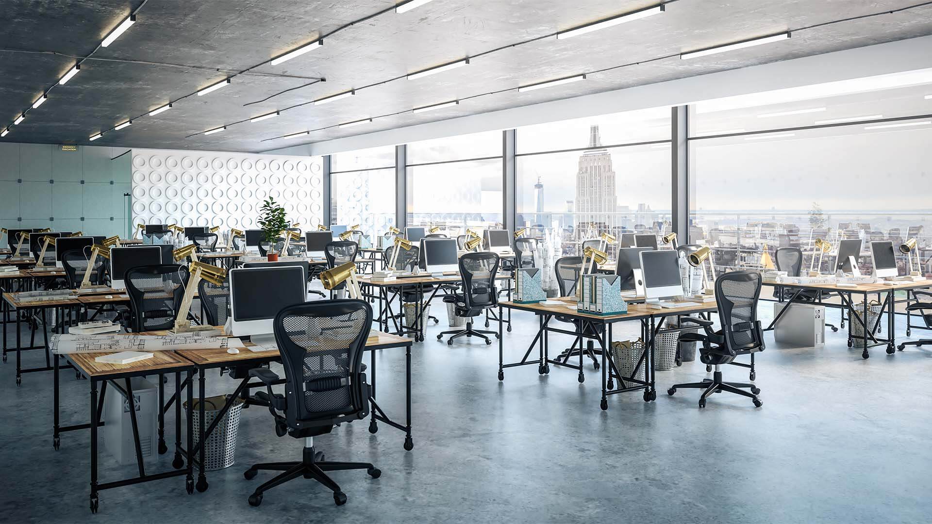 Open plan office with desks, desktop computers, files, large windows and high ceilings