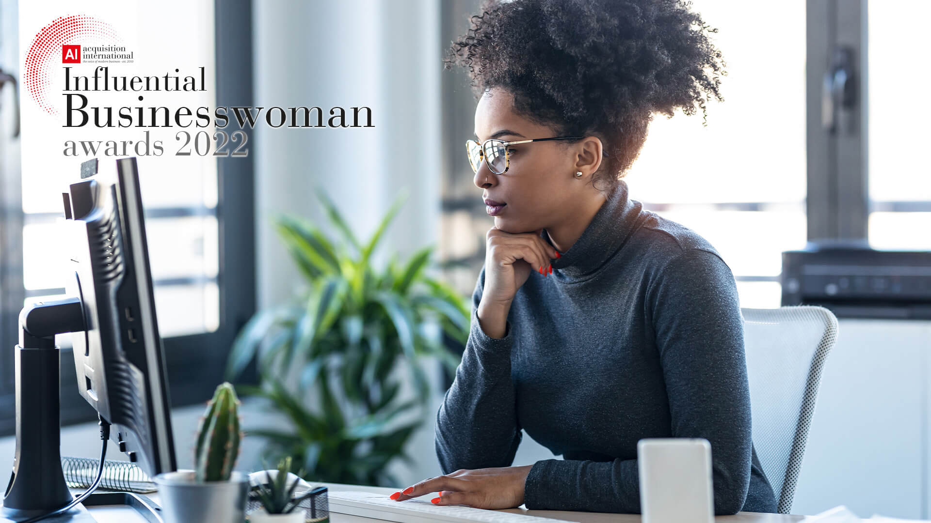 Businesswoman at her desk in her office. The 2022 Influential Businesswoman Awards logo is in the top left corner.