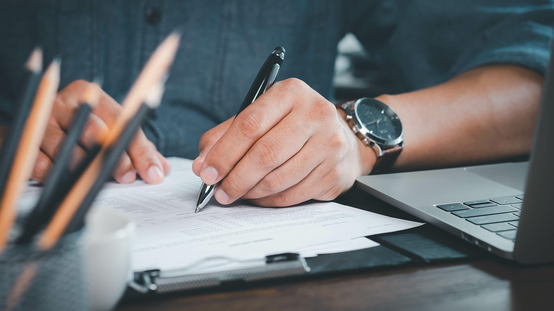 Close-up of Hand using writing pen with questionnaire or paperwork survey question filling in business company personal information form