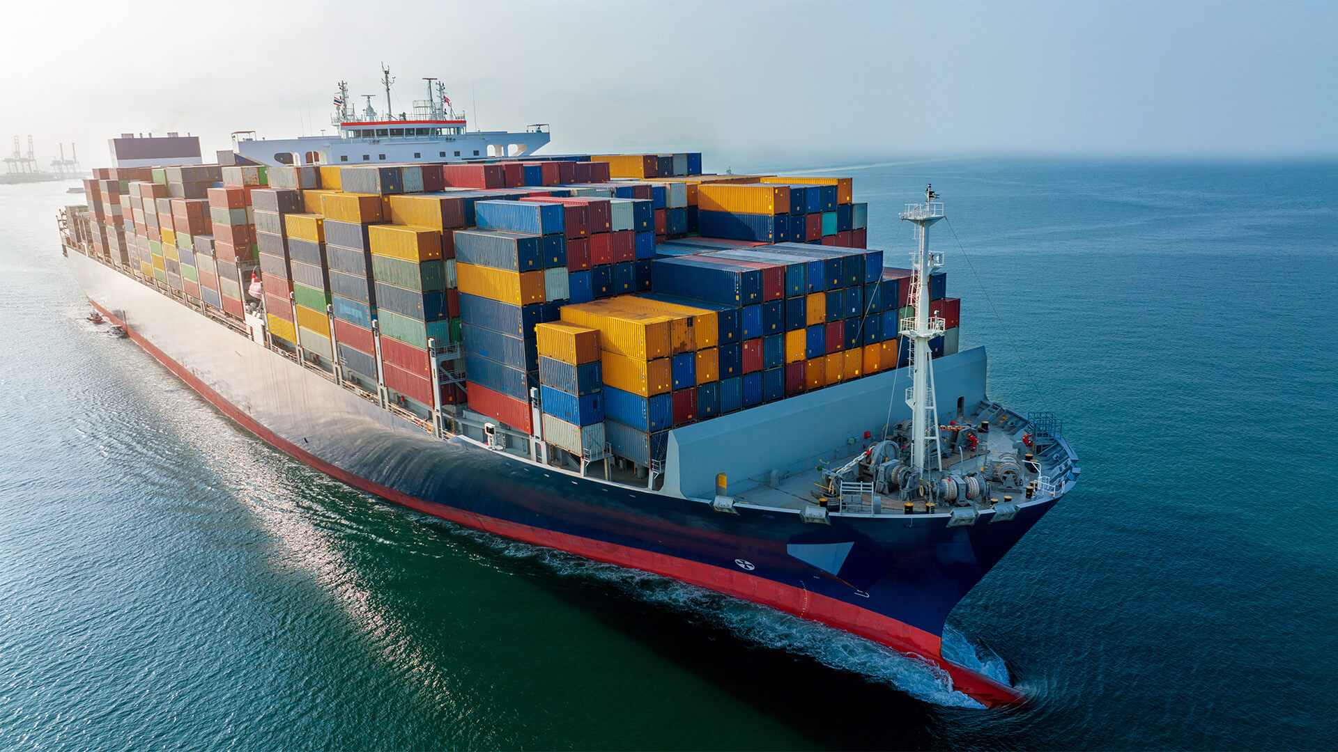 Aerial side view of cargo ship carrying container and running for export cargo yard port