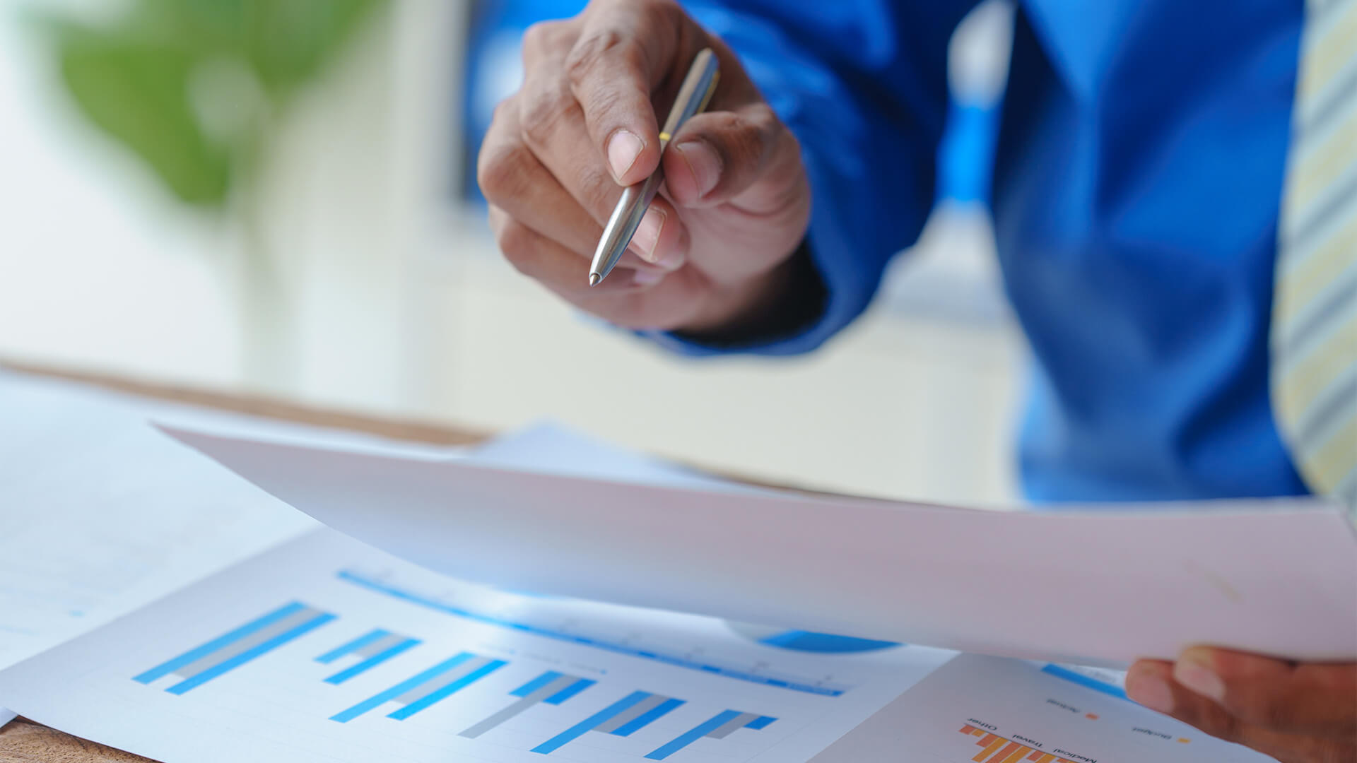 man holding pen in one hand and paper with graph on in other hand